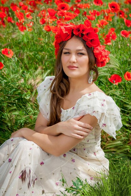 Hermosa mujer sentada en la flor de amapola