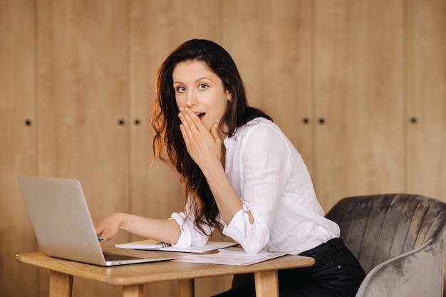 Hermosa mujer sentada en la oficina trabajando en una laptop