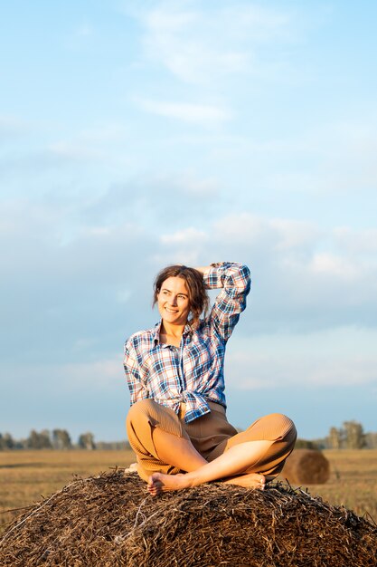 hermosa mujer sentada en el pajar, campo