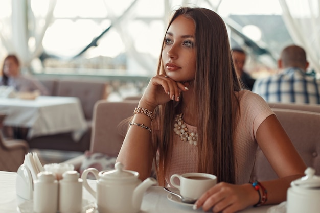 Hermosa mujer sentada en un restaurante y bebiendo té.