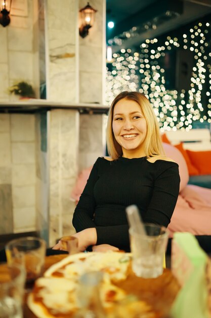 Hermosa mujer sentada en una silla en el pub y sonríe mujer vestida de negro está disfrutando de una gran velada en ...