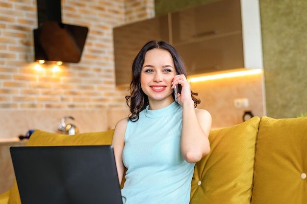 Hermosa mujer sentada en un sofá en casa con una laptop