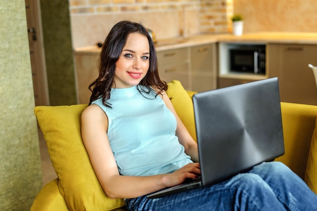 Foto hermosa mujer sentada en un sofá en casa con una laptop