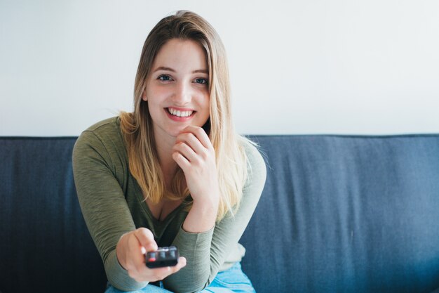 Hermosa mujer sentada en el sofá y viendo la televisión