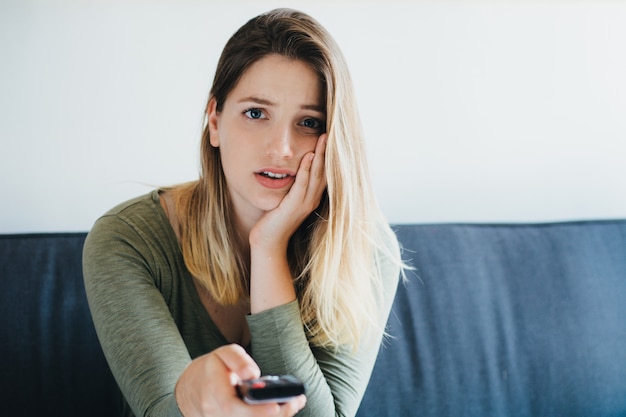 Hermosa mujer sentada en el sofá y viendo la televisión