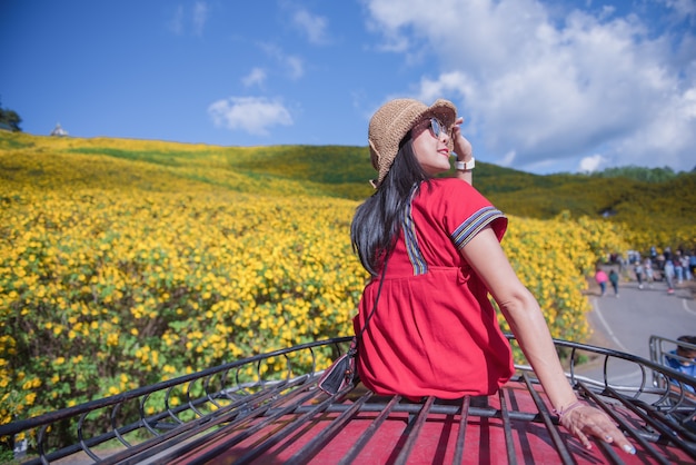 Una hermosa mujer sentada en el techo de un coche rojo