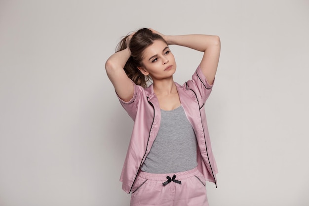 Hermosa mujer sexy con estilo en un camisón de lencería rosa de moda sobre un fondo gris