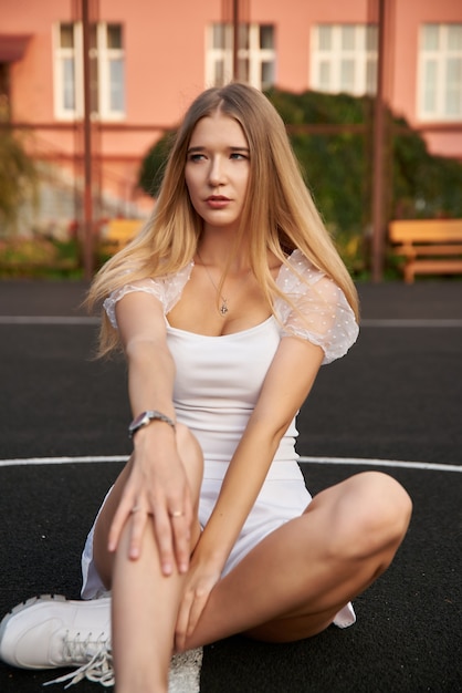 Hermosa mujer sexy posando al aire libre en la calle, joven y bella mujer en la cancha de baloncesto.