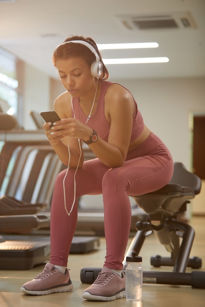 Hermosa mujer con smartphone en gimnasio