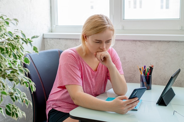 Hermosa mujer con smartphone y tableta. Trabajando desde casa. Las compras en línea