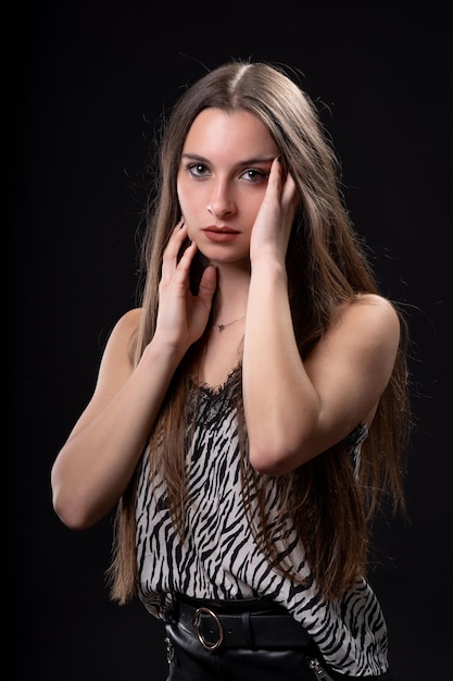 Hermosa mujer sobre fondo negro en falda de cuero y camisa estampada