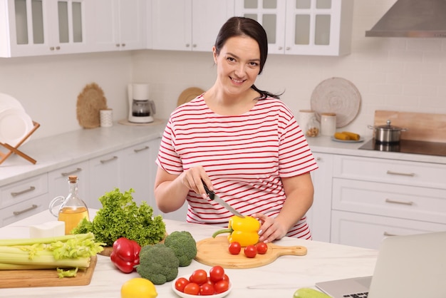 Hermosa mujer con sobrepeso preparando comida saludable en la mesa en la cocina