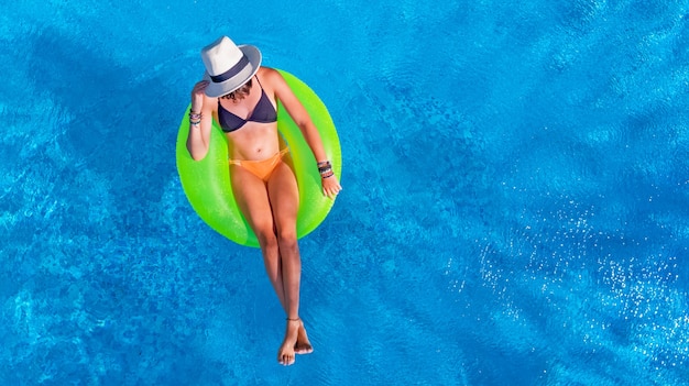 Hermosa mujer con sombrero en la piscina en el anillo inflable en el agua de vacaciones