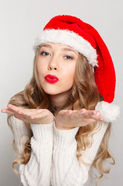 Hermosa mujer con sombrero de santa que sopla besos.