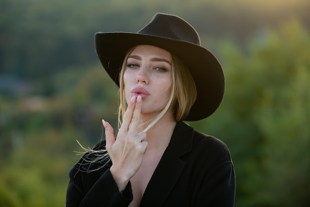 Hermosa mujer con sombrero simula disparar con los dedos Moda y belleza Vaquera con sombrero de vaquero con pistola de dedos