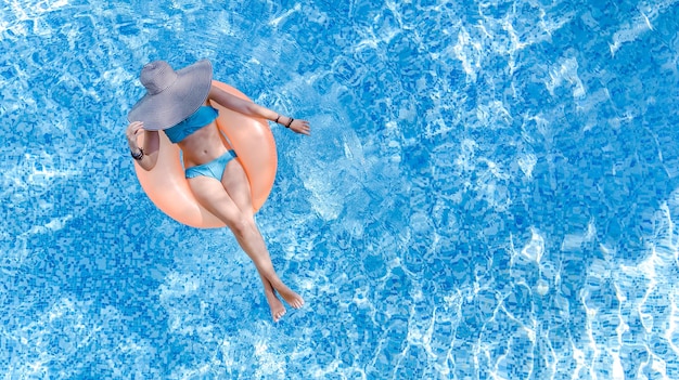 Foto hermosa mujer con sombrero en la vista superior aérea de la piscina desde arriba, la joven en bikini se relaja