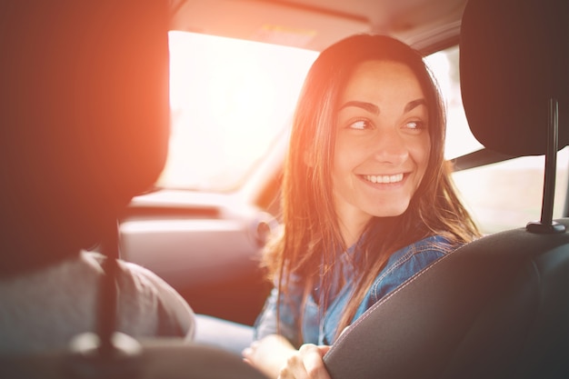 Hermosa mujer sonriendo mientras está sentado en los asientos del pasajero delantero en el coche