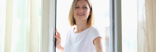 Hermosa mujer sonriente abre una puerta de cristal