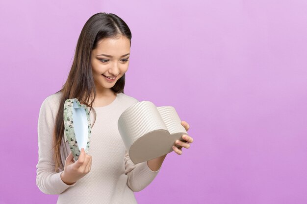 Hermosa mujer sonriente con cabello largo sosteniendo caja de regalo