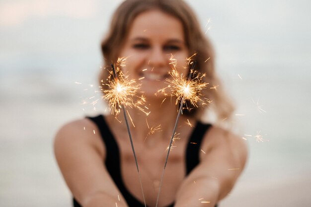 Hermosa mujer sonriente con chispas en la playa