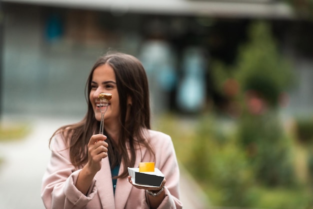 Una hermosa mujer sonriente come poffertjes frescos mientras recorre la ciudad Enfoque selectivo Foto de alta calidad