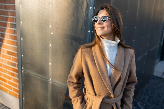 Hermosa mujer sonriente con elegante abrigo y gafas de sol al aire libre