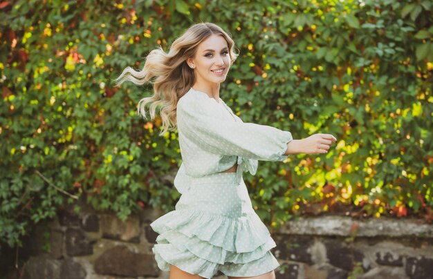 Hermosa mujer sonriente emocionada en ropa de primavera de moda al aire libre modelo elegante femenino caminando...