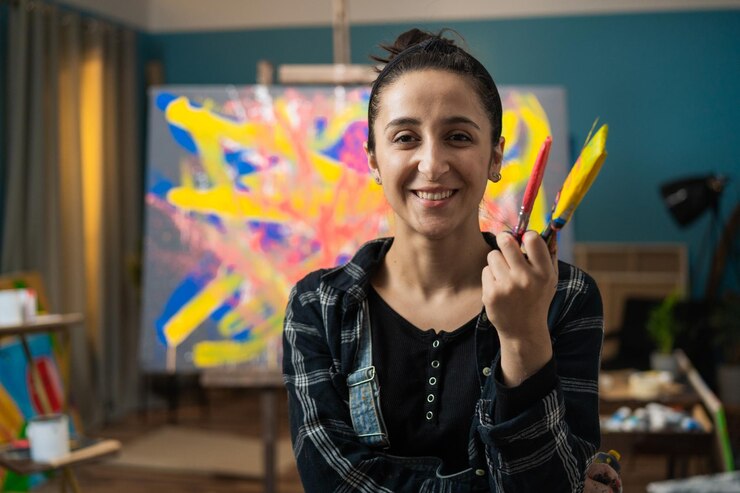 Foto una hermosa mujer sonriente se encuentra en un estudio de pintura contra un caballete con un lienzo