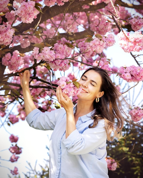 Hermosa mujer sonriente en el fondo de flores de cerezo rosa lila