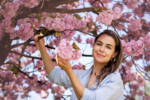 Hermosa mujer sonriente en el fondo de flores de cerezo rosa lila