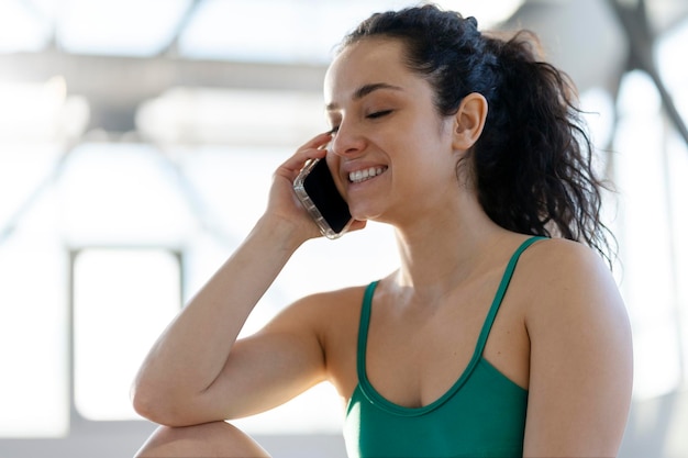 Hermosa mujer sonriente en el gimnasio hablando por teléfono inteligente Concepto de capacitación en atención médica