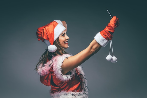 Hermosa mujer sonriente joven en traje de Santa Claus tomando un selfie con smartphone.