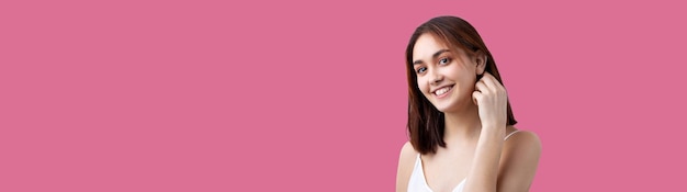 Hermosa mujer sonriente con maquillaje natural de piel limpia y dientes blancos en un fondo Pacific Pink