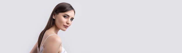 Hermosa mujer sonriente con maquillaje natural de piel limpia y dientes blancos sobre un fondo gris