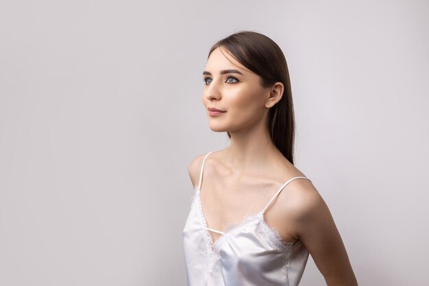 Hermosa mujer sonriente con maquillaje natural de piel limpia y dientes blancos sobre un fondo gris