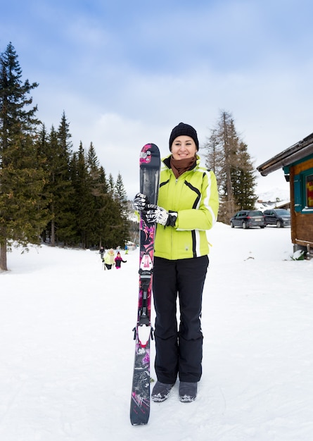 Hermosa mujer sonriente posando en la cima de la pendiente con esquís