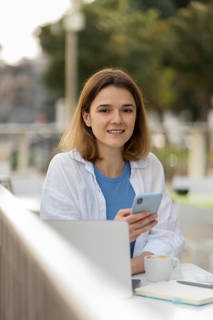 Hermosa mujer sonriente sosteniendo un teléfono inteligente navegando en el sitio web, comunicación en línea