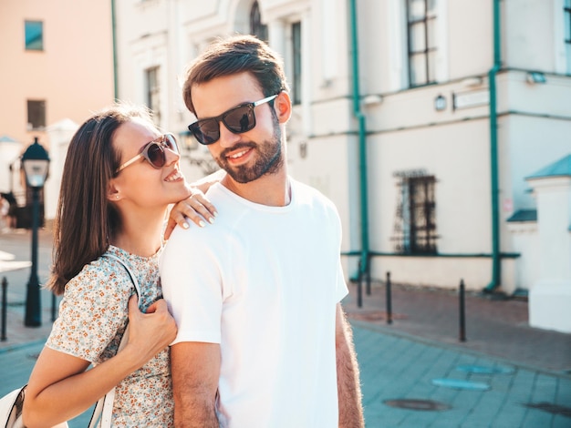 Hermosa mujer sonriente y su guapo novio Mujer con ropa casual de verano Familia feliz y alegre Mujer divirtiéndose Pareja posando en el fondo de la calle con gafas de sol Abrazándose unos a otros