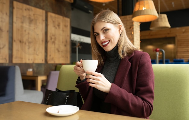 Hermosa mujer sonriente tomando café en la cafetería.