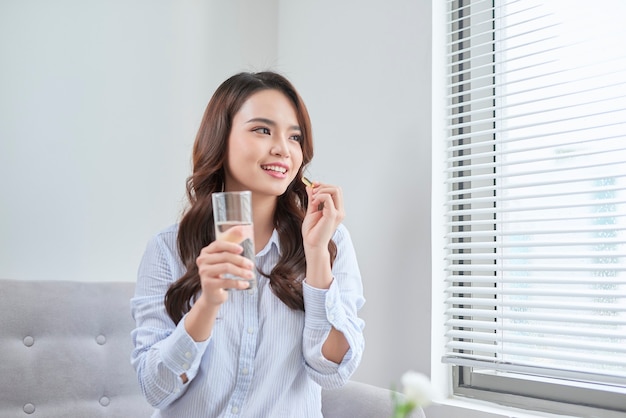 Hermosa mujer sonriente tomando píldoras de vitamina. Suplemento dietético