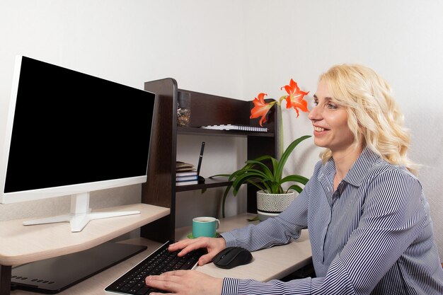 Una hermosa mujer sonriente trabaja en casa en la computadora Trabajar en casa