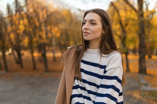 Hermosa mujer sonriente en traje elegante sentada en la mesa con un sombrero y un suéter romántico estado de ánimo feliz esperando a un novio en una cita en un café tendencia de la moda de primavera y verano tomando café