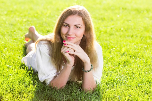 Hermosa mujer sonriente tumbada en un césped al aire libre Ella es absolutamente feliz