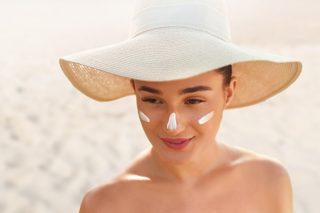 Hermosa mujer sonrisa aplicando crema solar en la cara Cuidado de la piel Cuerpo Protección solar protector solar