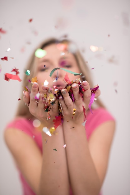 Hermosa mujer soplando confeti en el aire fiesta celebración de año nuevo aislado sobre fondo blanco.