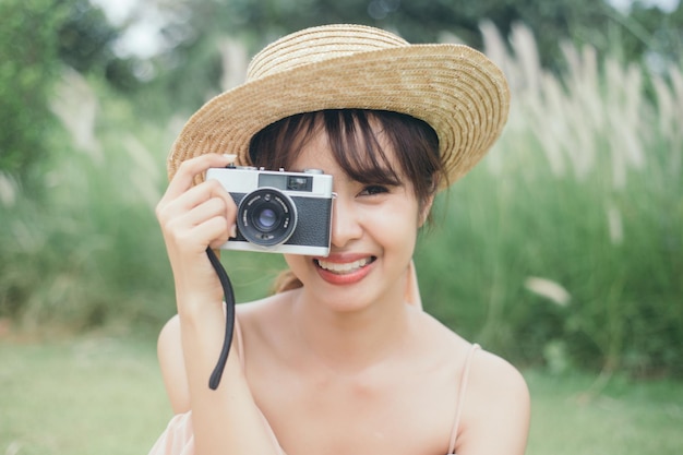 Hermosa mujer sostenga una cámara vintage en el jardín