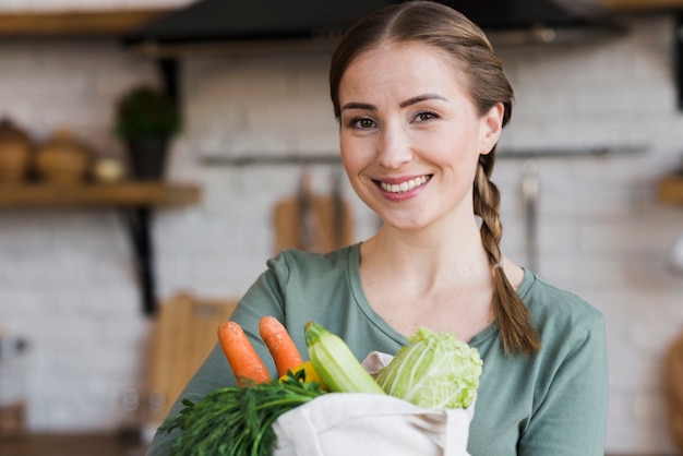 Hermosa mujer sosteniendo la bolsa con verduras orgánicas