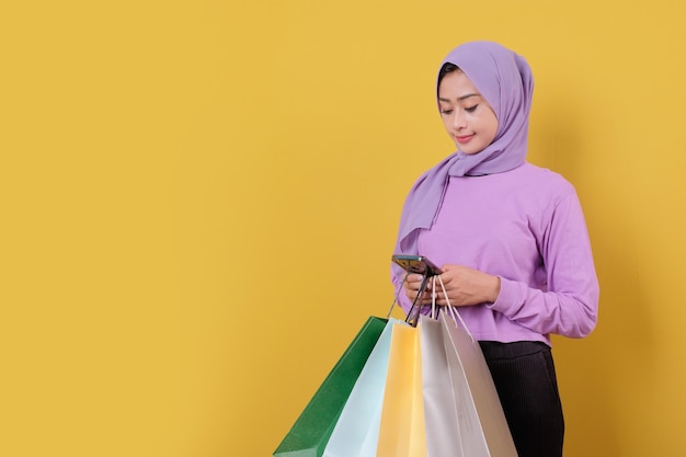 Foto hermosa mujer sosteniendo bolsas de la compra, muy bien y de buen humor, mediante teléfono móvil