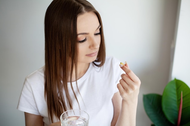 Hermosa mujer sosteniendo una cápsula con una fuente de aceite de pescado de ácidos grasos Omega3