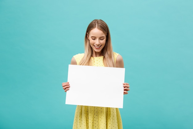 Hermosa mujer sosteniendo un cartel en blanco aislado sobre fondo azul